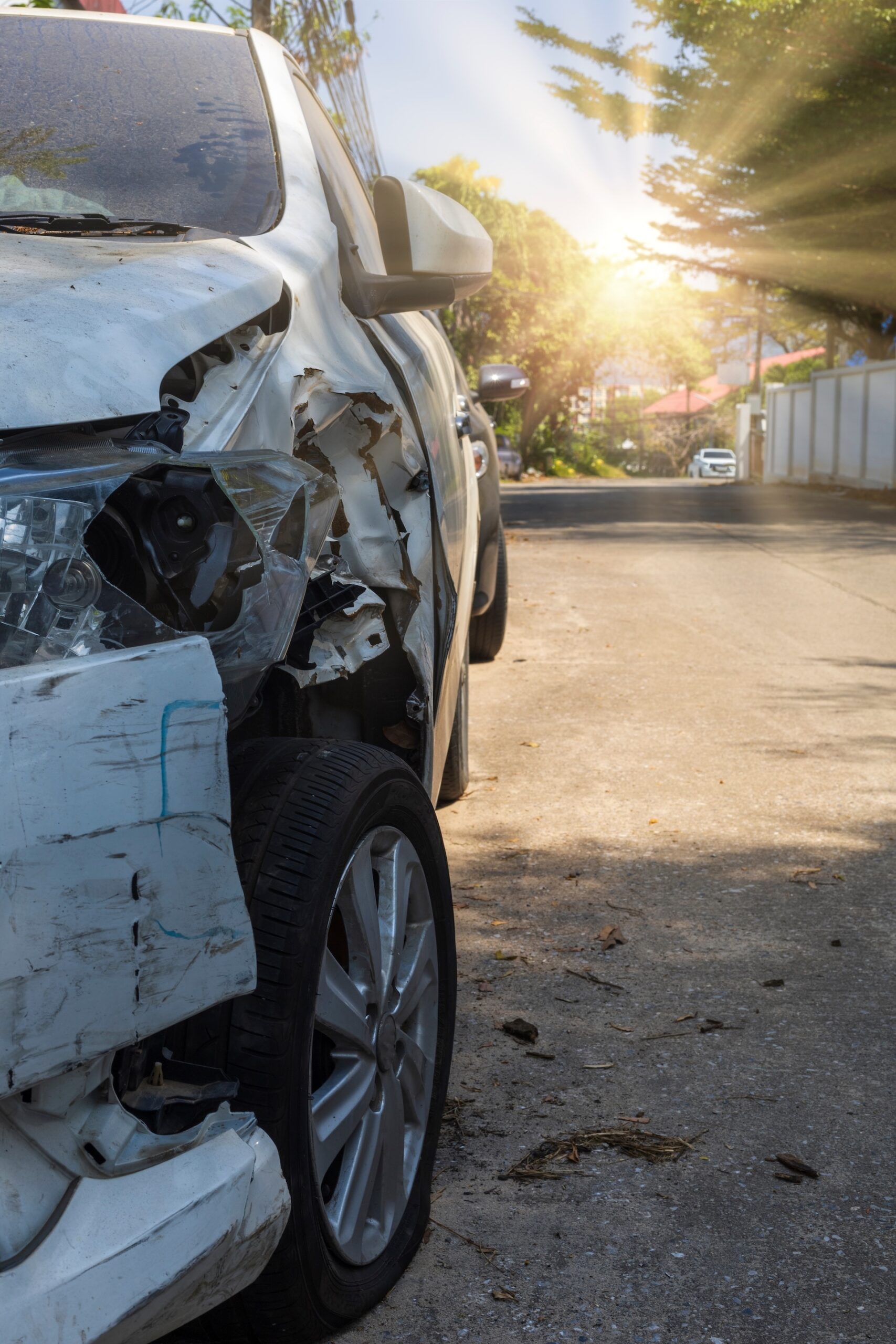 A smiling child in a yellow top playfully covers the eyes of both adults sitting beside her at a table with papers, books, and a laptop. The adults react with amusement in a cozy home setting.
