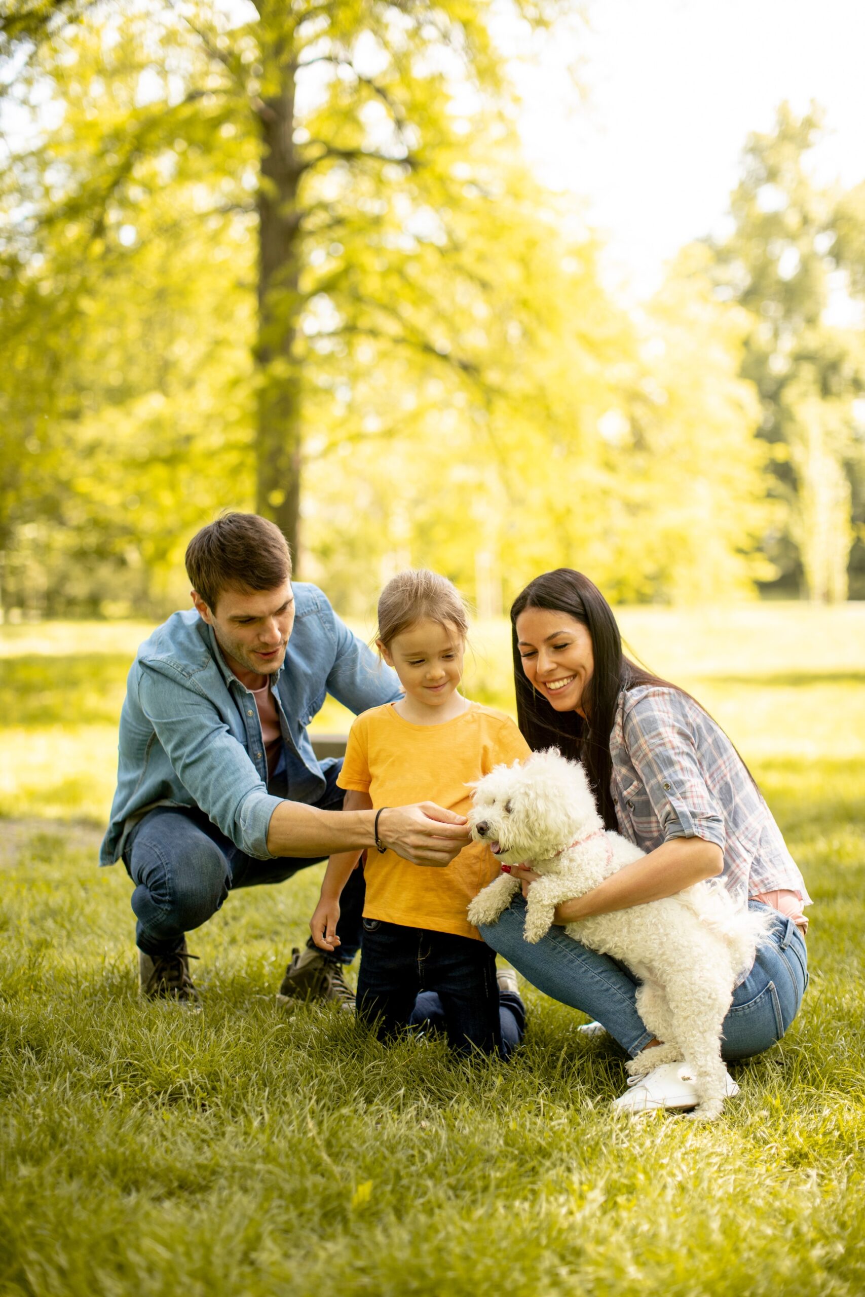 A woman and a man sit closely with a young girl between them. The adults appear comforting and supportive as the girl looks down with a thoughtful expression. The scene suggests a caring family moment.